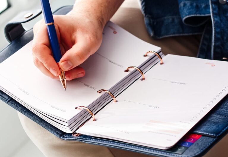 Focused image of a hand writing in a planner for schedule organization.