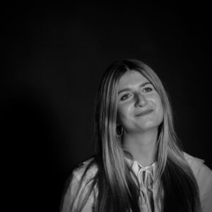 A graceful black and white portrait of a smiling young woman with long blonde hair.